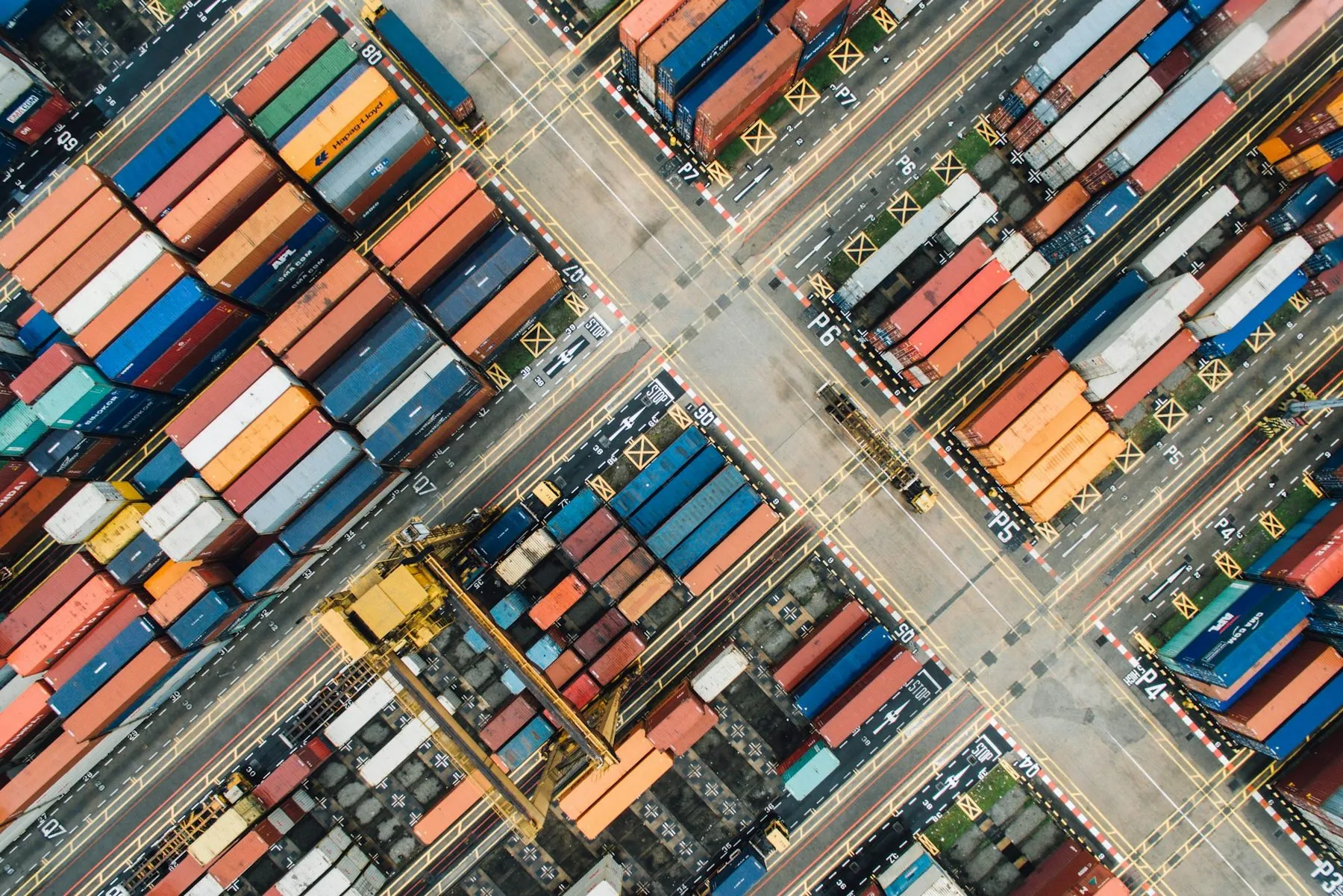 An overhead view of stacked shipping containers and straddle carriers in a container terminal
