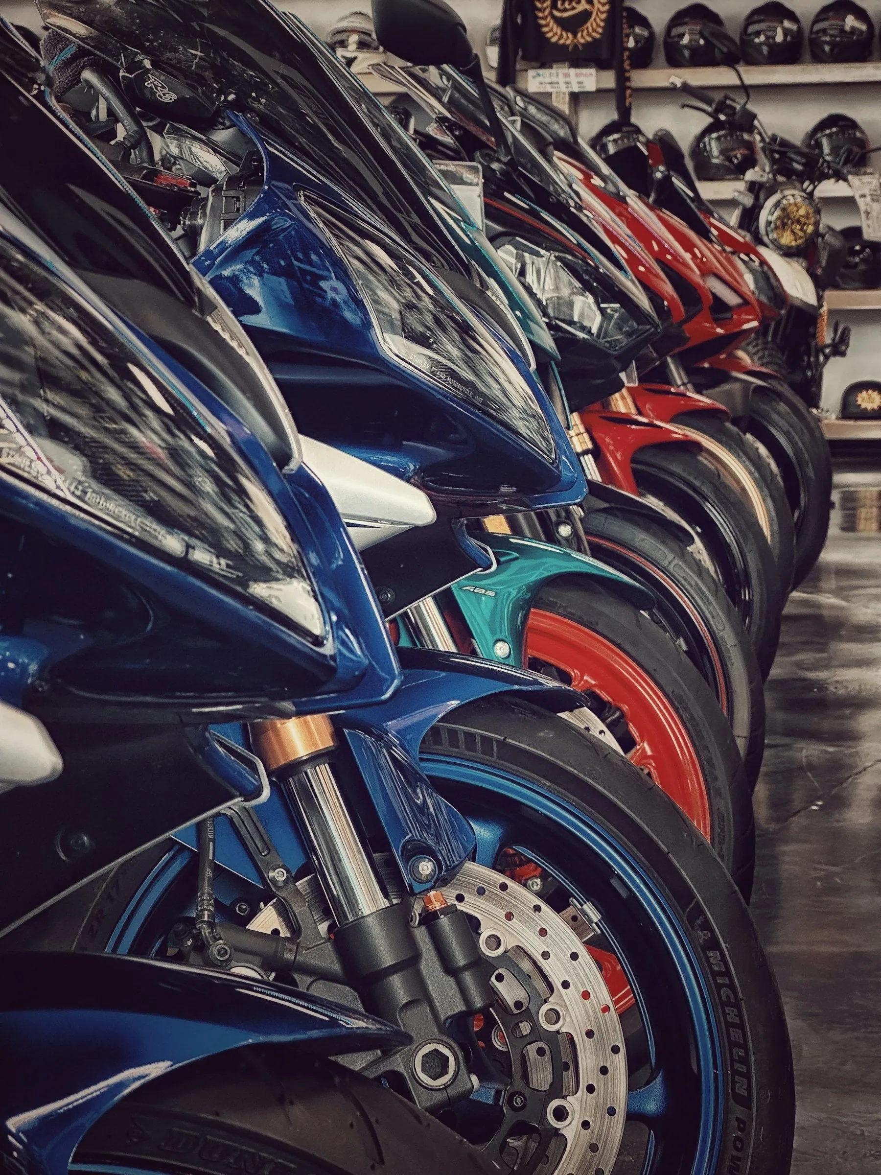 A tight row of motorcycles lined up front wheel to front wheel inside a showroom