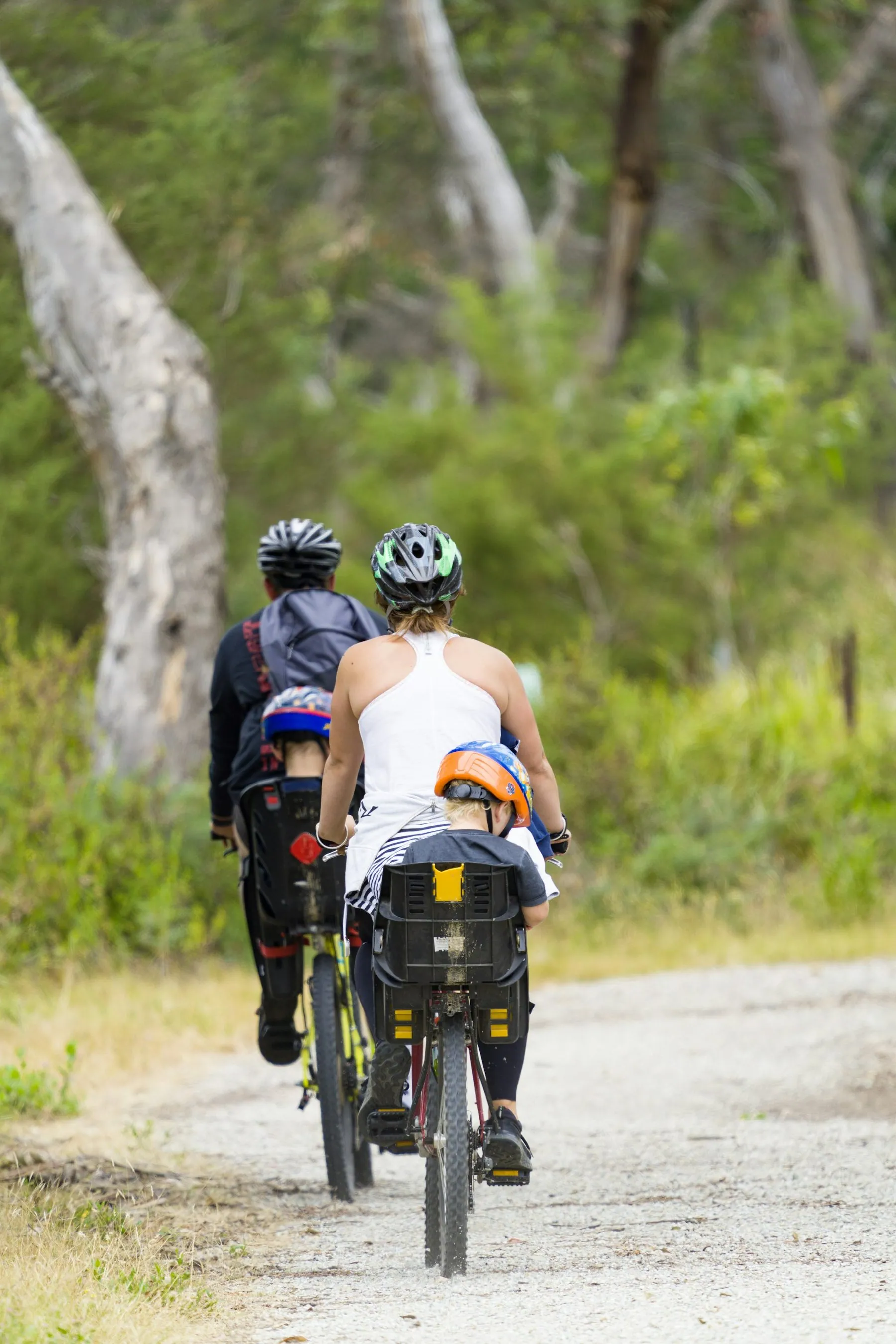 Two riders on fully loaded touring bicycles with rear panniers seen from behind on a dirt track