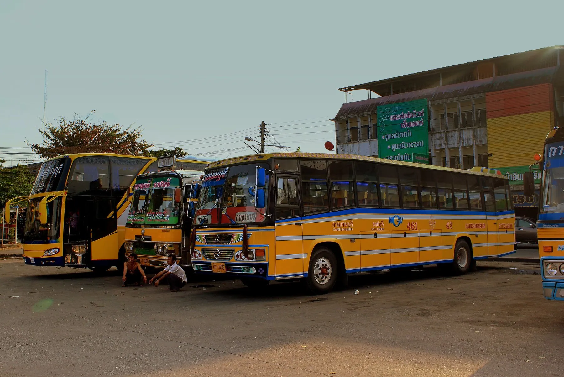 Yellow and blue intercity coaches drawn up side by side on the apron at Kanchanaburi bus station