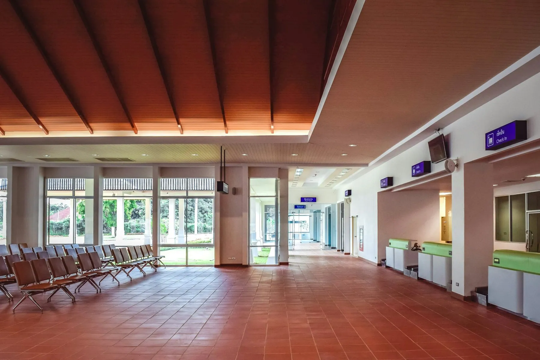 Empty rows of waiting-room chairs facing a counter in a Thai public office hall