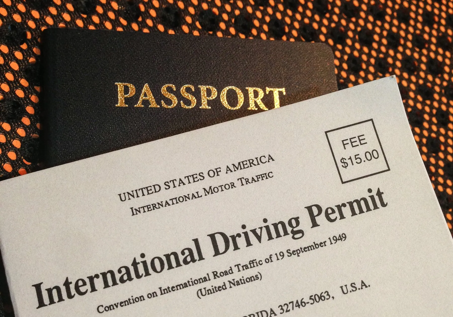 A grey International Driving Permit booklet lying on top of a passport
