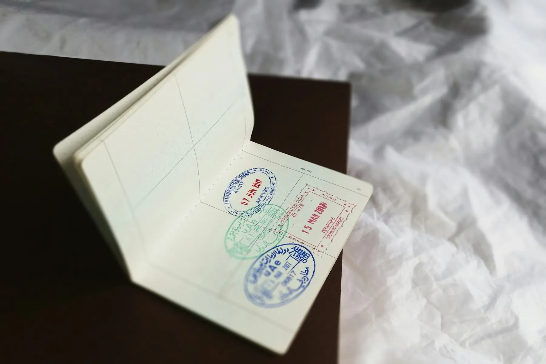 Close-up of an open passport page covered in blue and red entry stamps