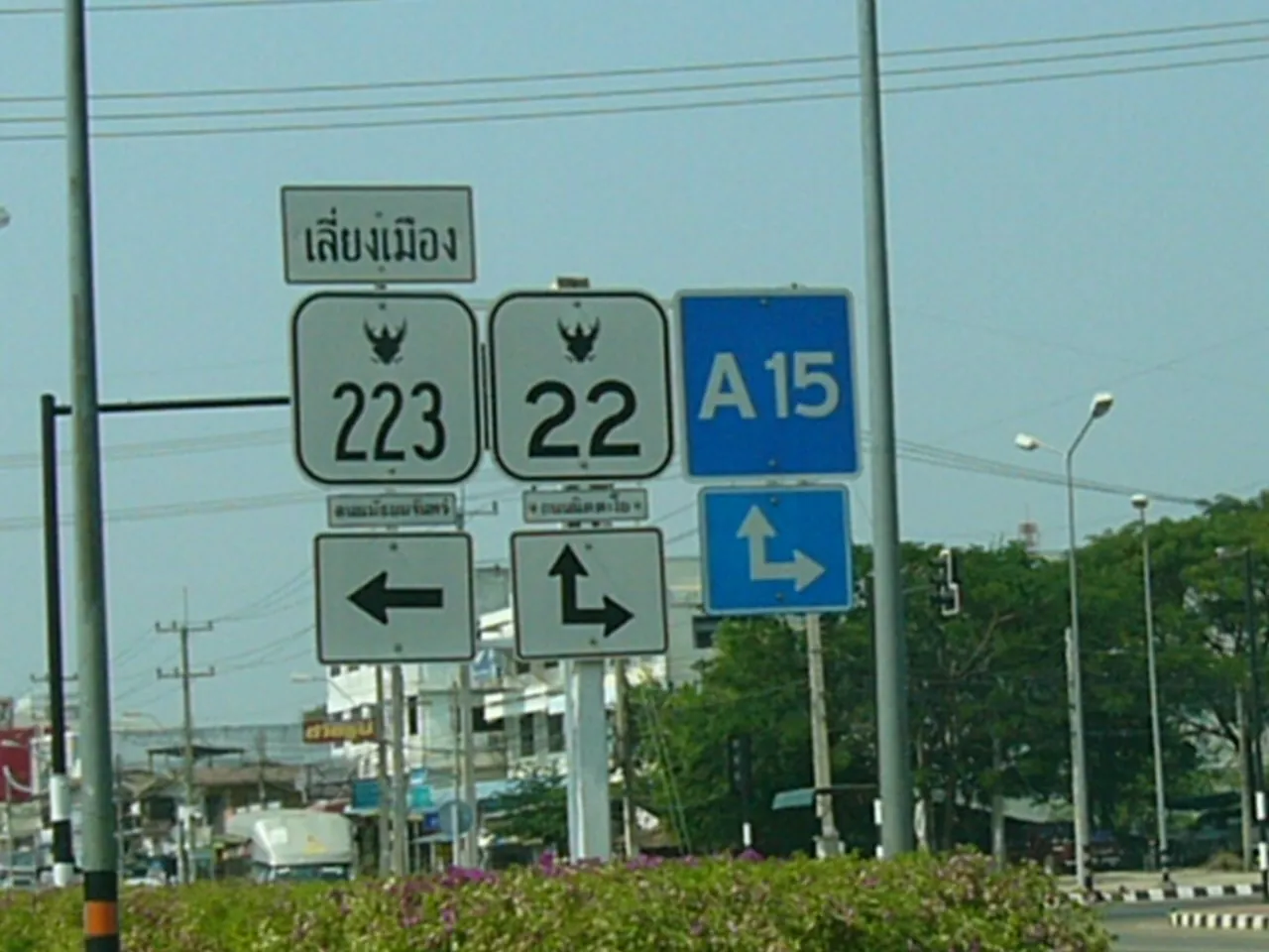 A cluster of Thai route-number and direction signs on a roadside post, with Thai script above them