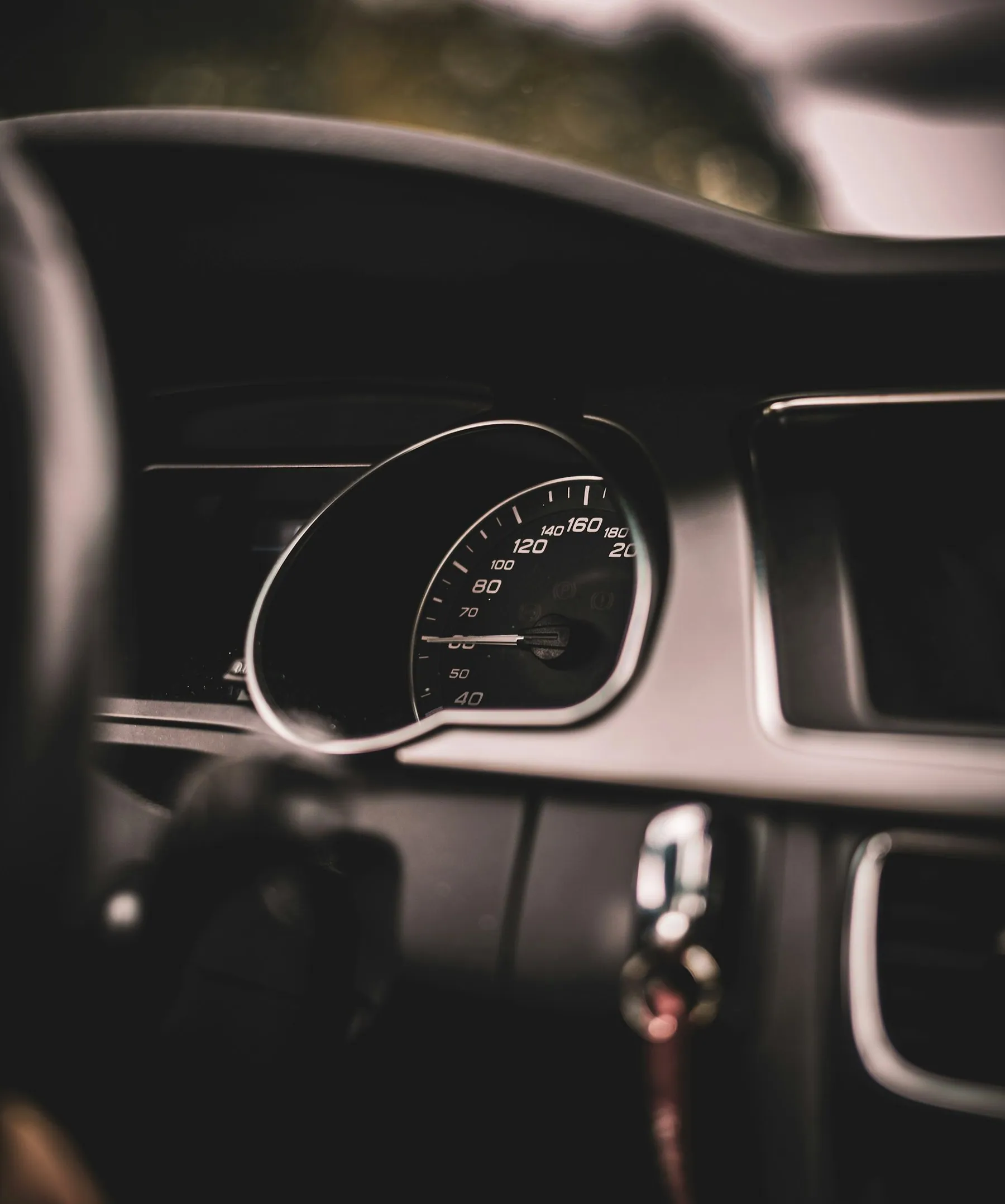 A driver's-eye view across a steering wheel to the speedometer and rev counter