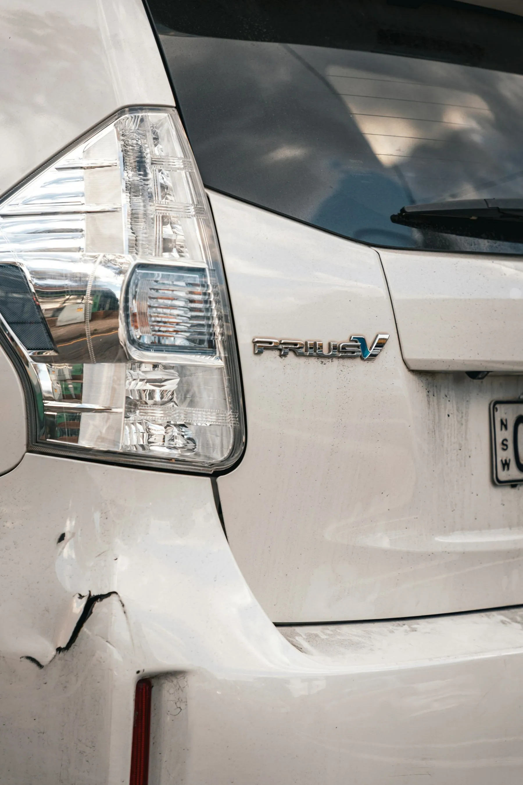 A shallow dent in the rear bumper of a silver hatchback, photographed close