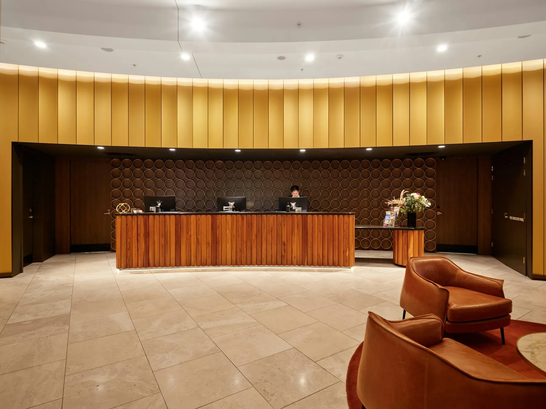 An empty hotel reception counter in a panelled lobby with armchairs to one side