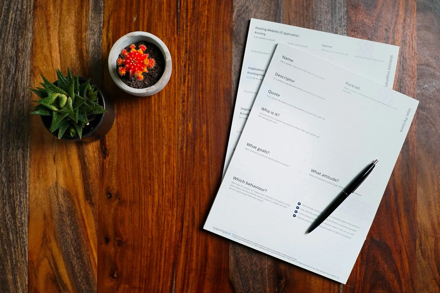 Two blank claim forms and a pen laid out on a dark wooden table