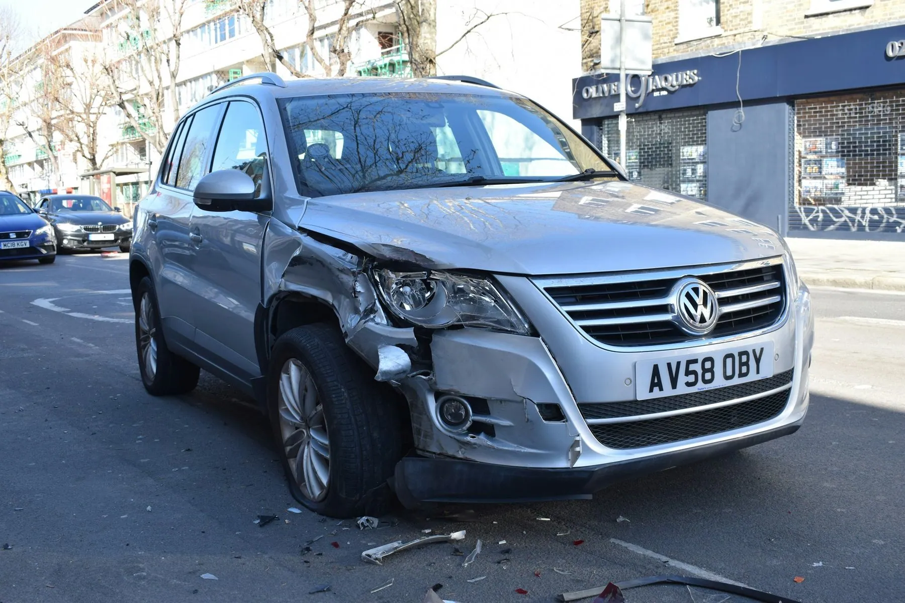 A silver SUV at the roadside with its front wing and bumper caved in