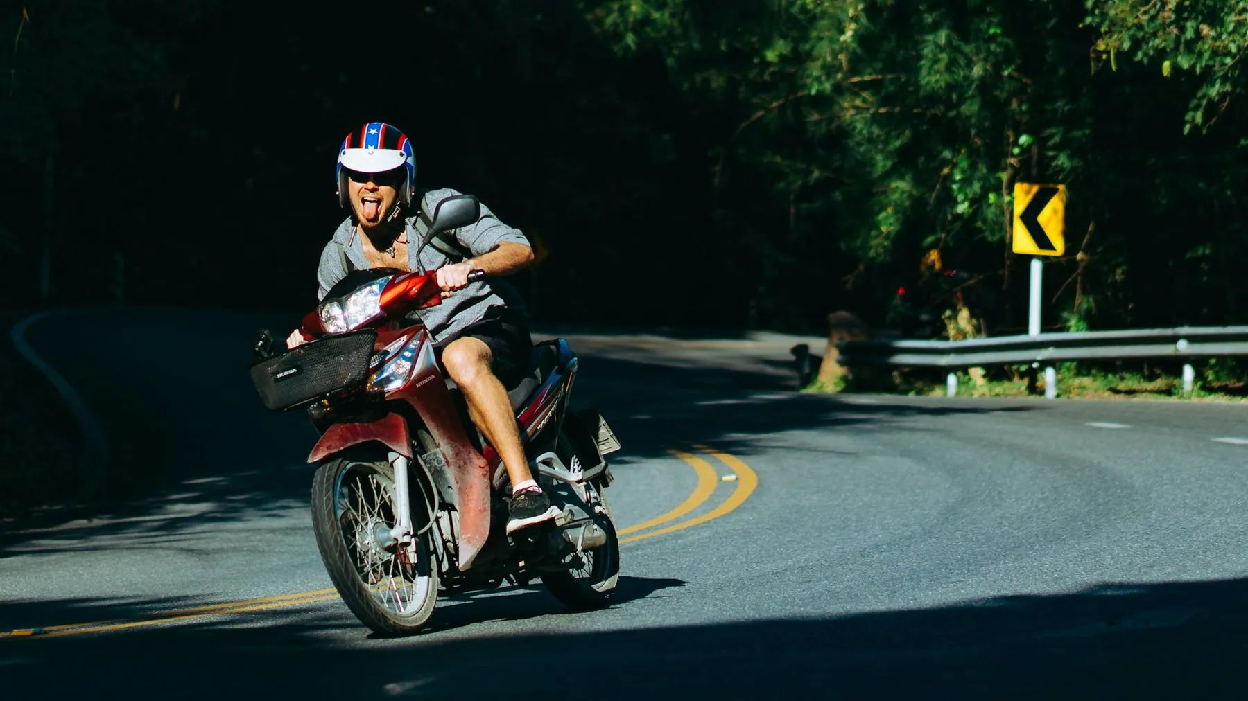 A rider with soft luggage strapped to the pillion leaning through a curve past a chevron sign