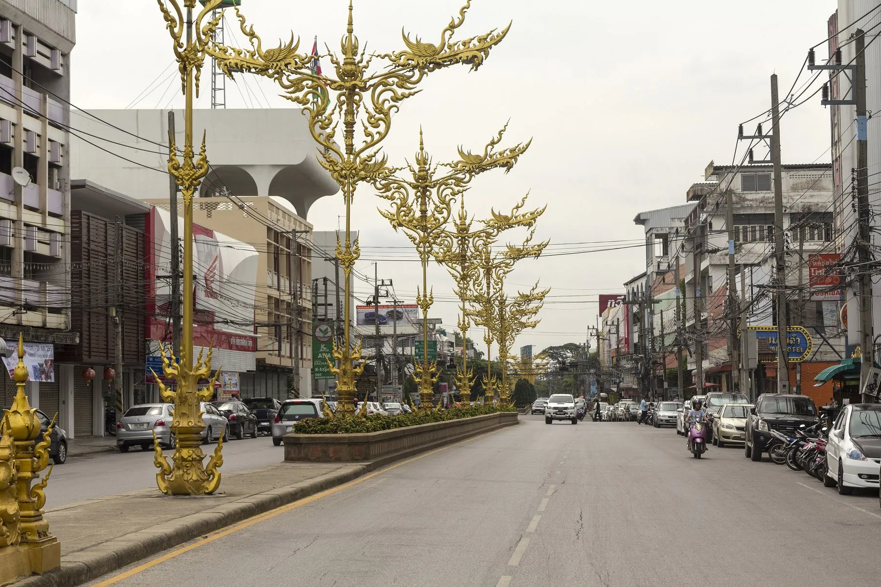 Gilded Lanna street lamps down the central reservation of Thanon Bap Prakan in Chiang Rai, cars and bikes either side