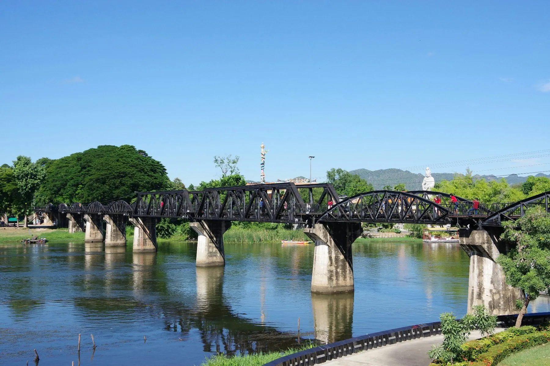 The black steel spans of the bridge over the River Kwai with the approach road curving in from the right