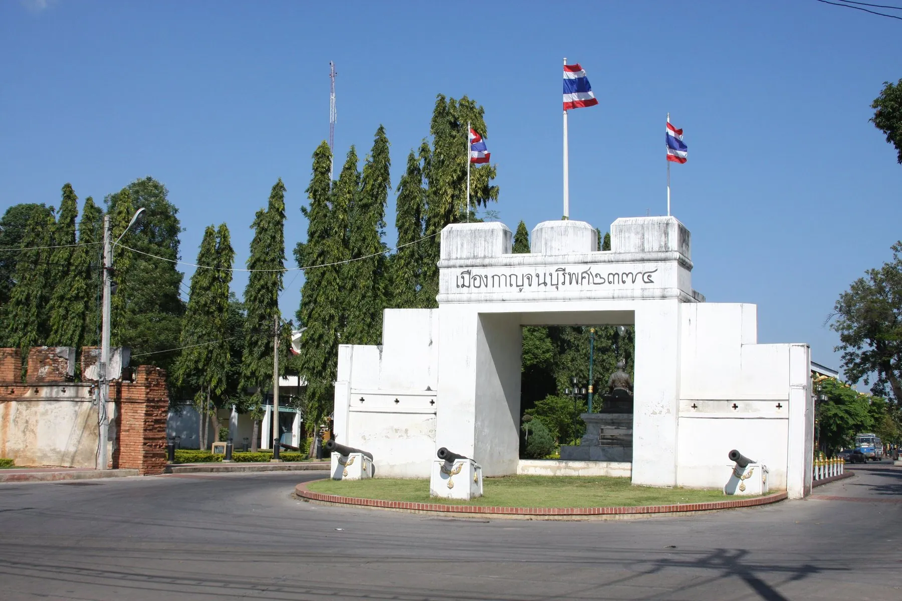 The white city gate of Kanchanaburi standing on its island in the middle of an empty road