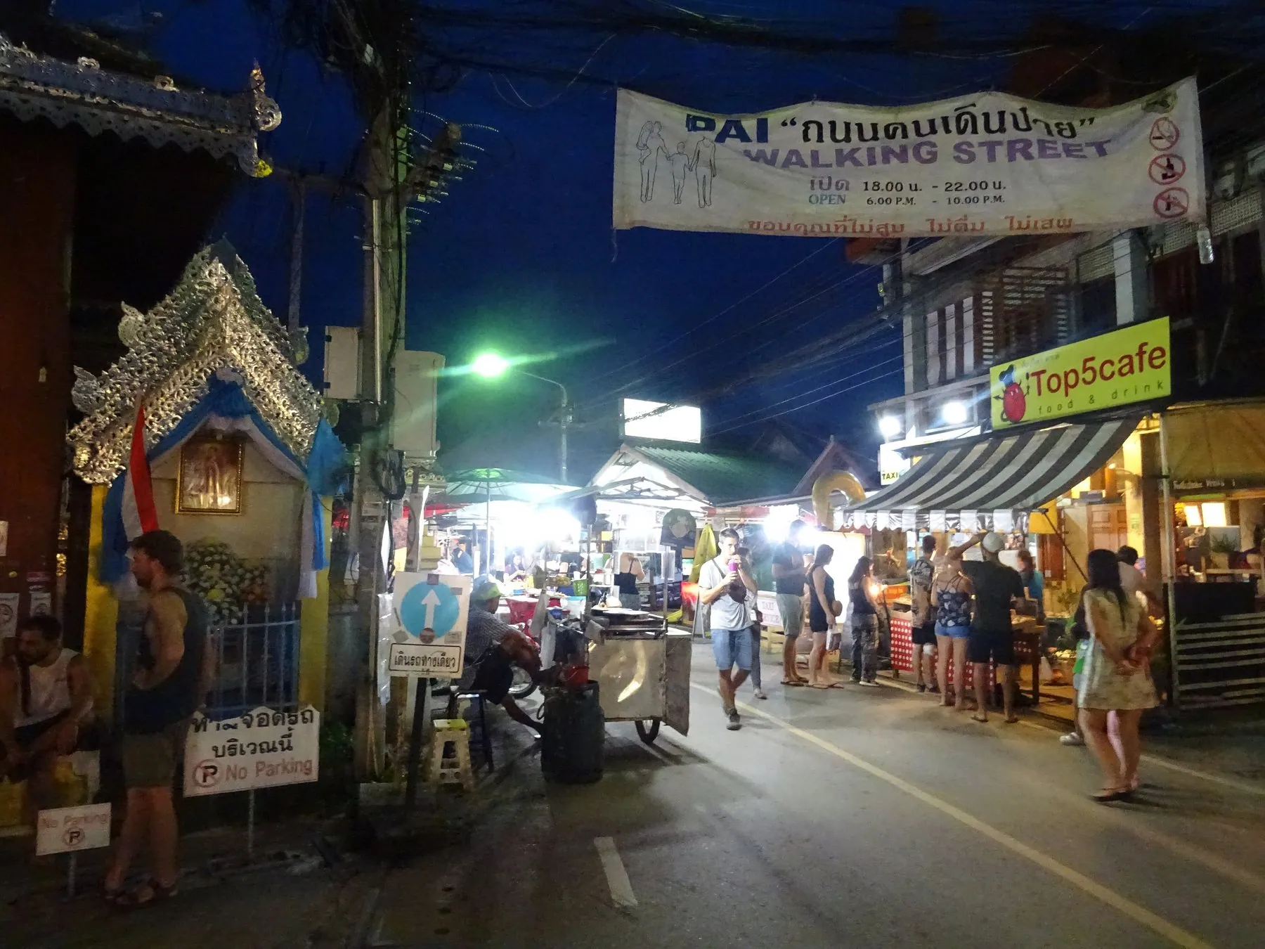 The Pai Walking Street banner strung over the road above night market stalls and browsing visitors