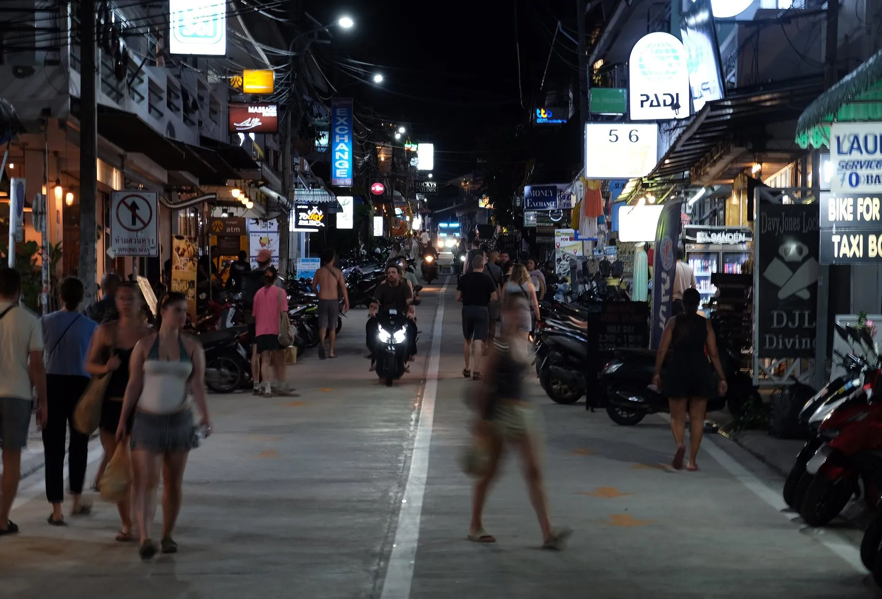Dive shops and parked motorbikes lining the Mae Haad street on Koh Tao after dark