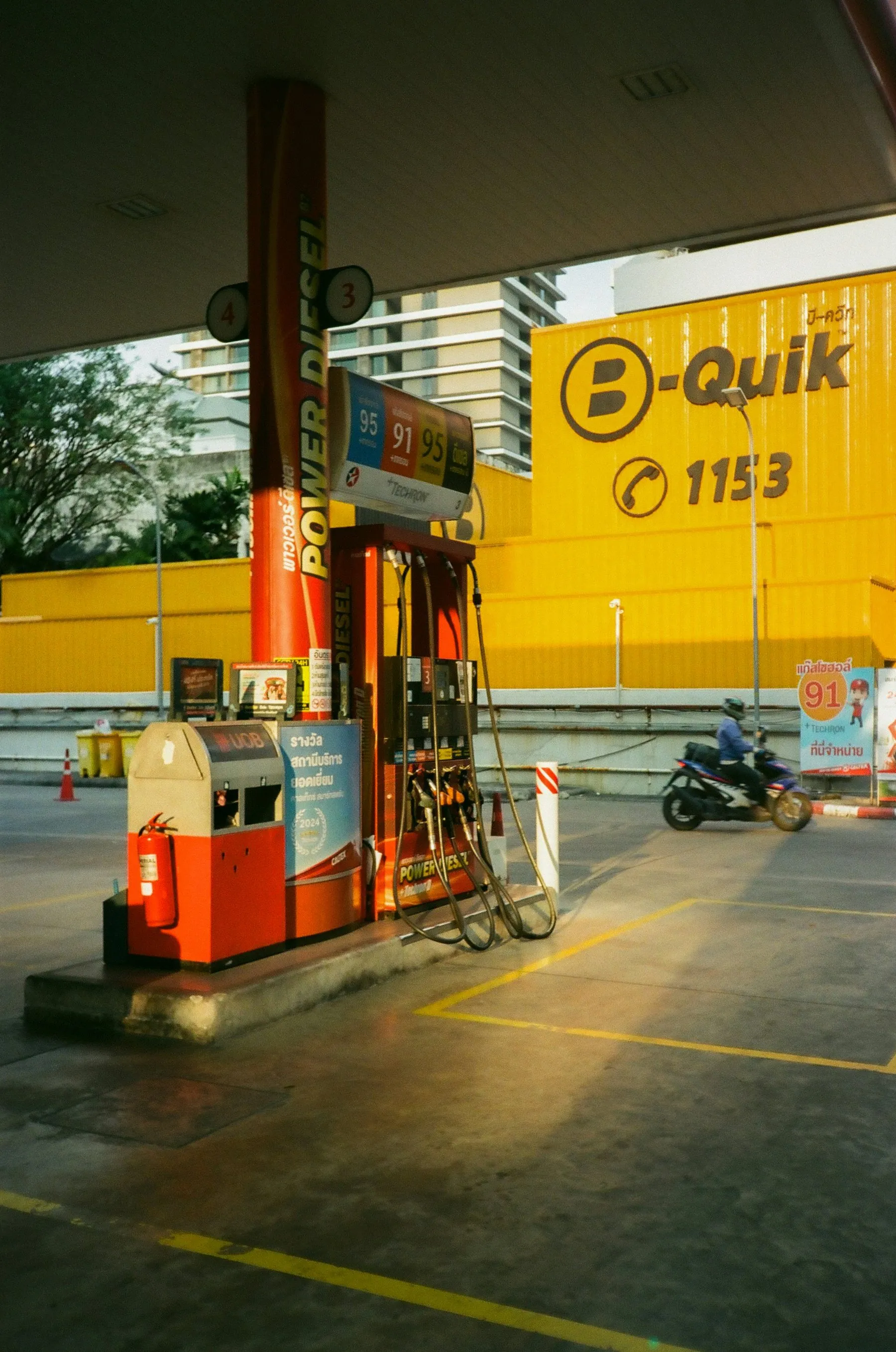 Motorbikes crossing the forecourt of a small Thai filling station