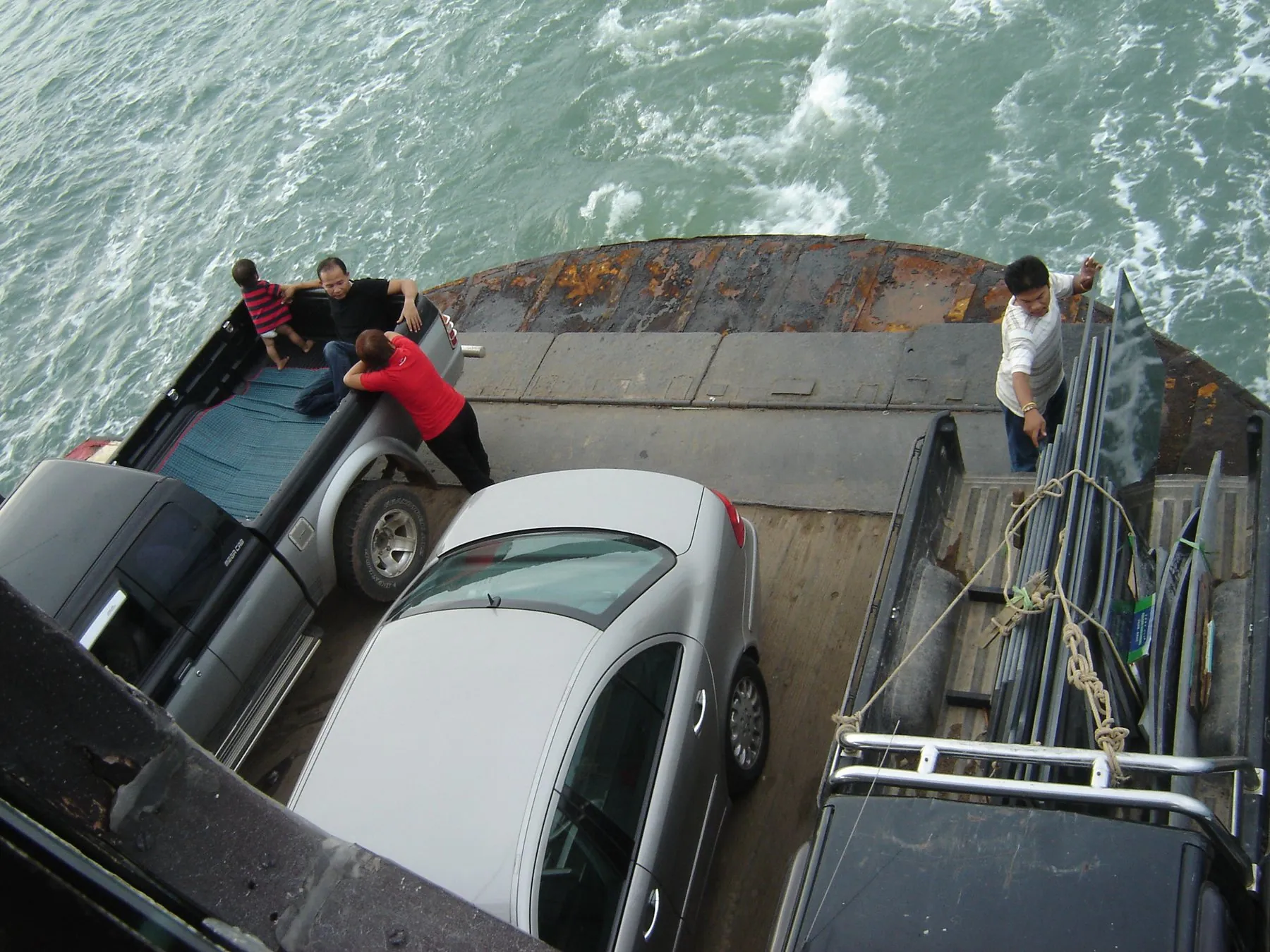 Cars parked nose to tail on the open deck of a Thai vehicle ferry with barely a door's width between them