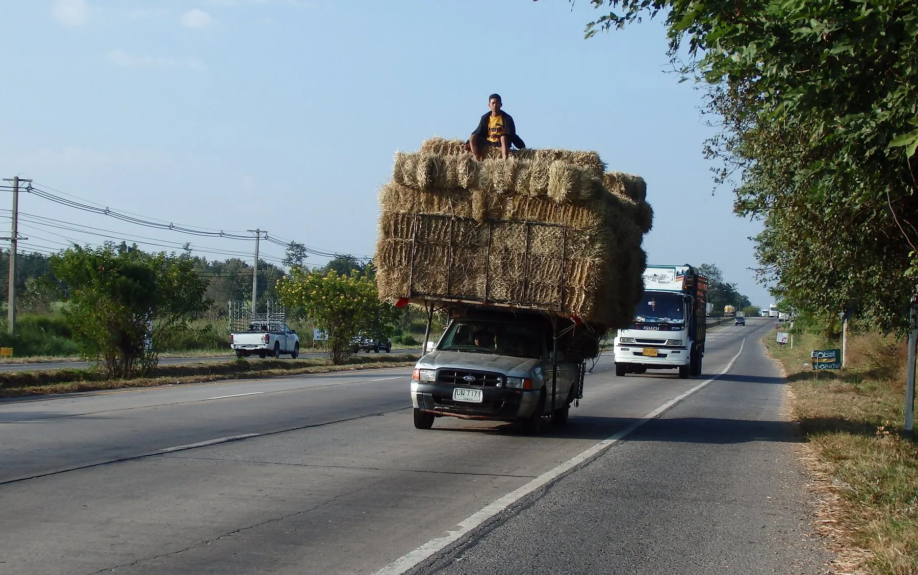 A pickup piled high above the cab with baled straw on Highway 2 near Khon Kaen