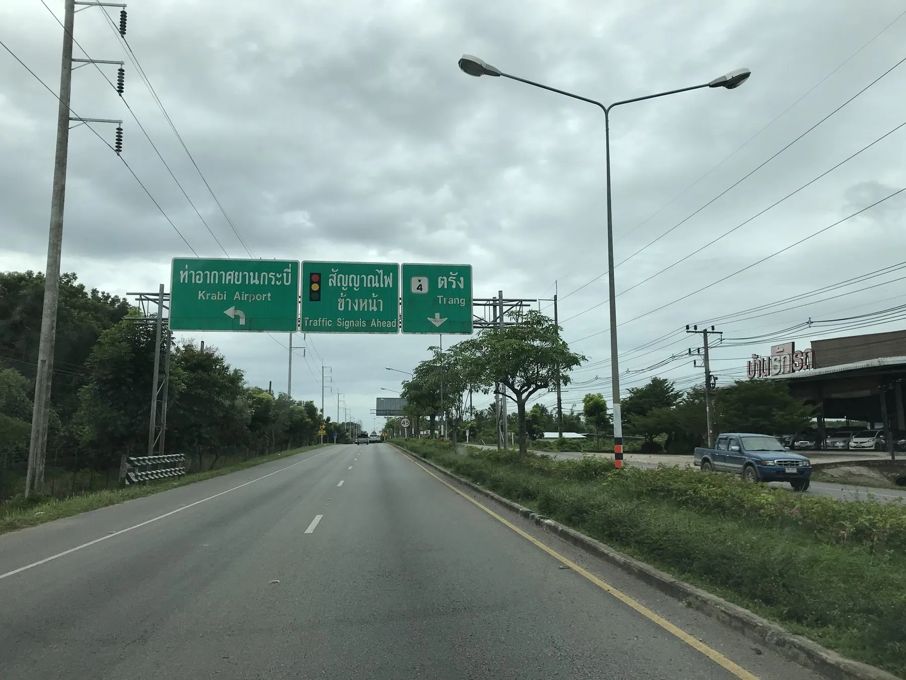Highway 4 in Krabi province approaching the airport junction, green direction signs over an empty carriageway