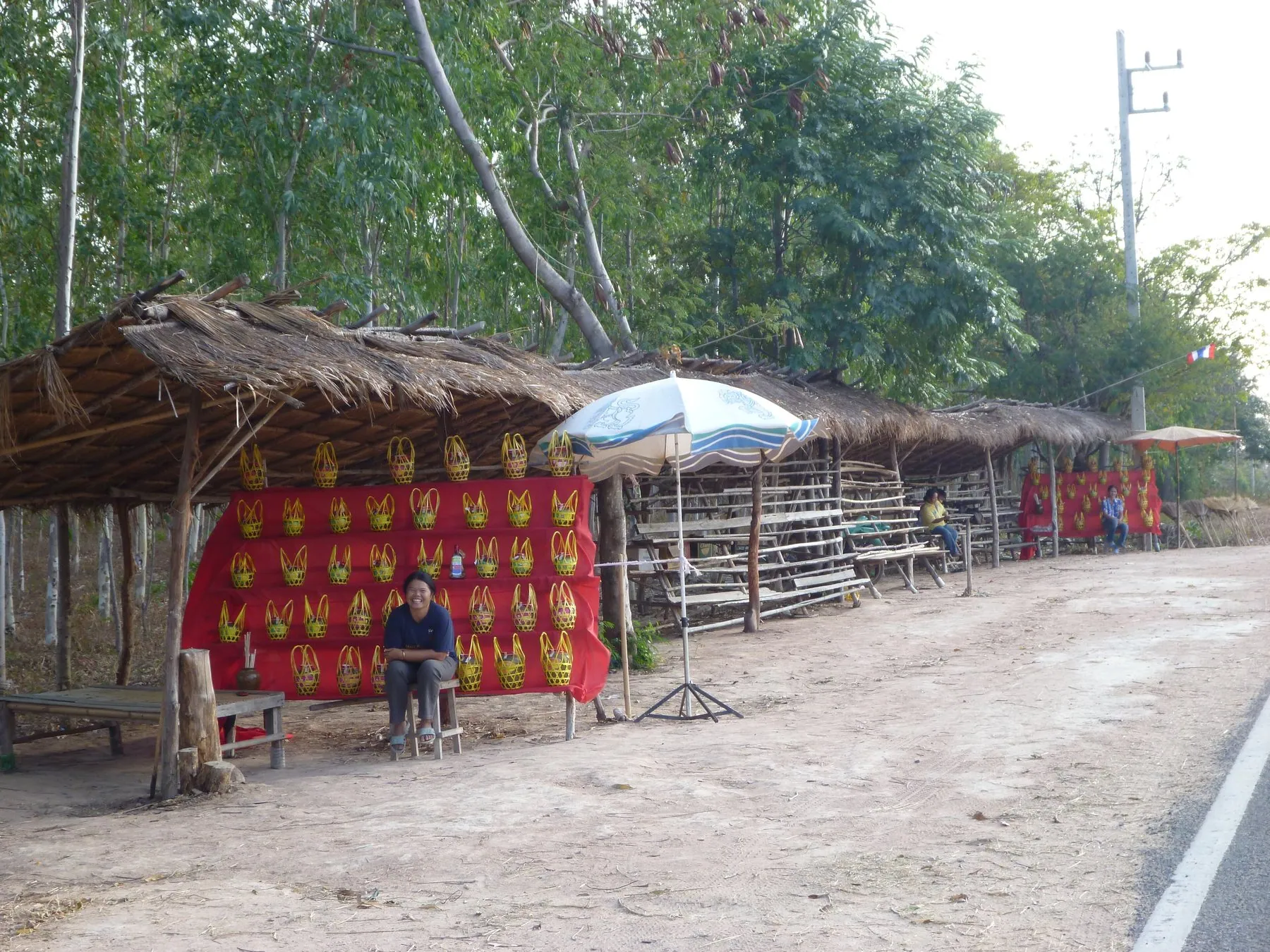 A roadside stall in Roi Et province stacked with melons under a thatched awning beside the highway