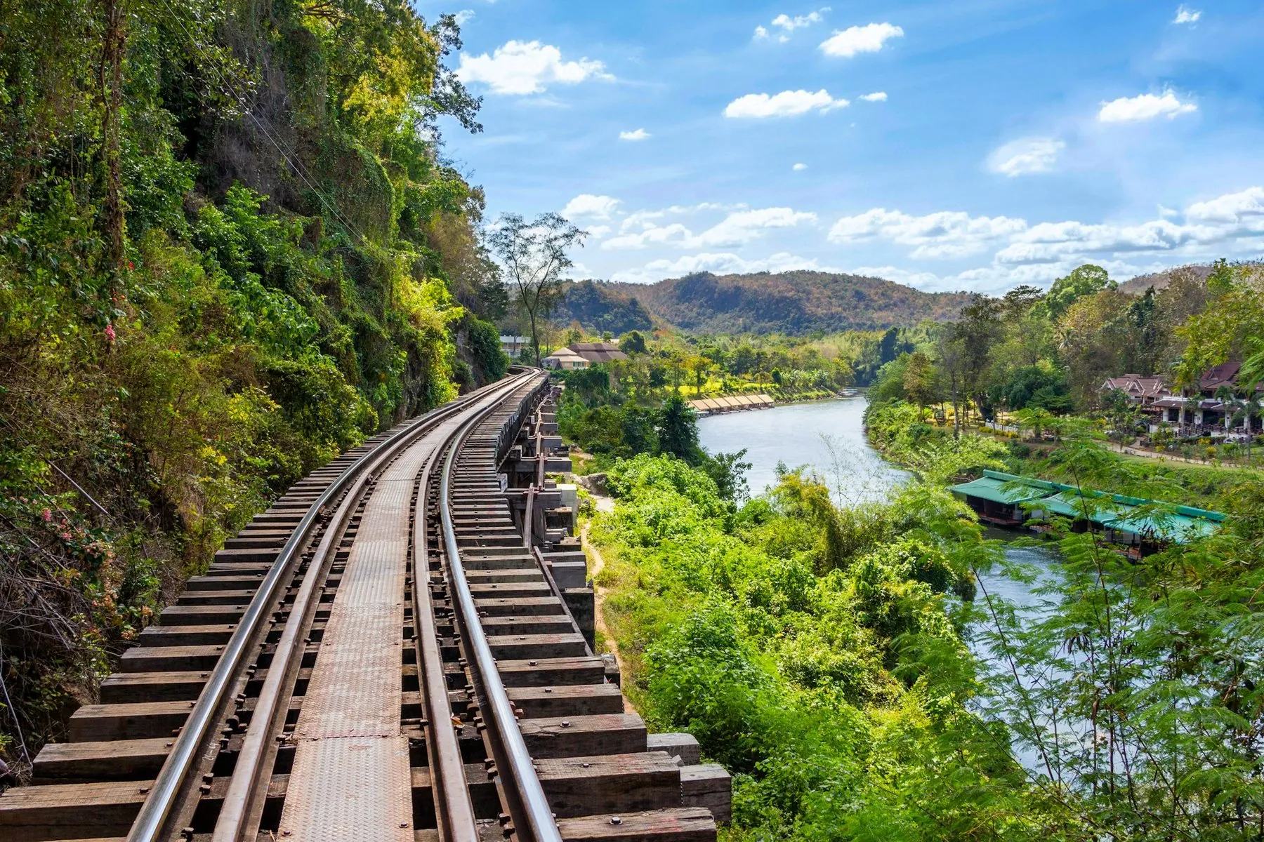 A train on the Death Railway running along a ledge above the river north of Kanchanaburi