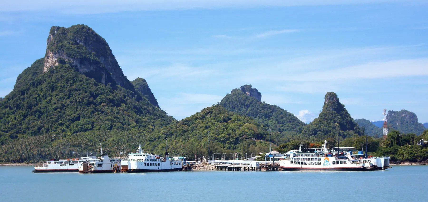 Red and white Raja ferries tied up at the Don Sak pier for Koh Samui with limestone hills behind