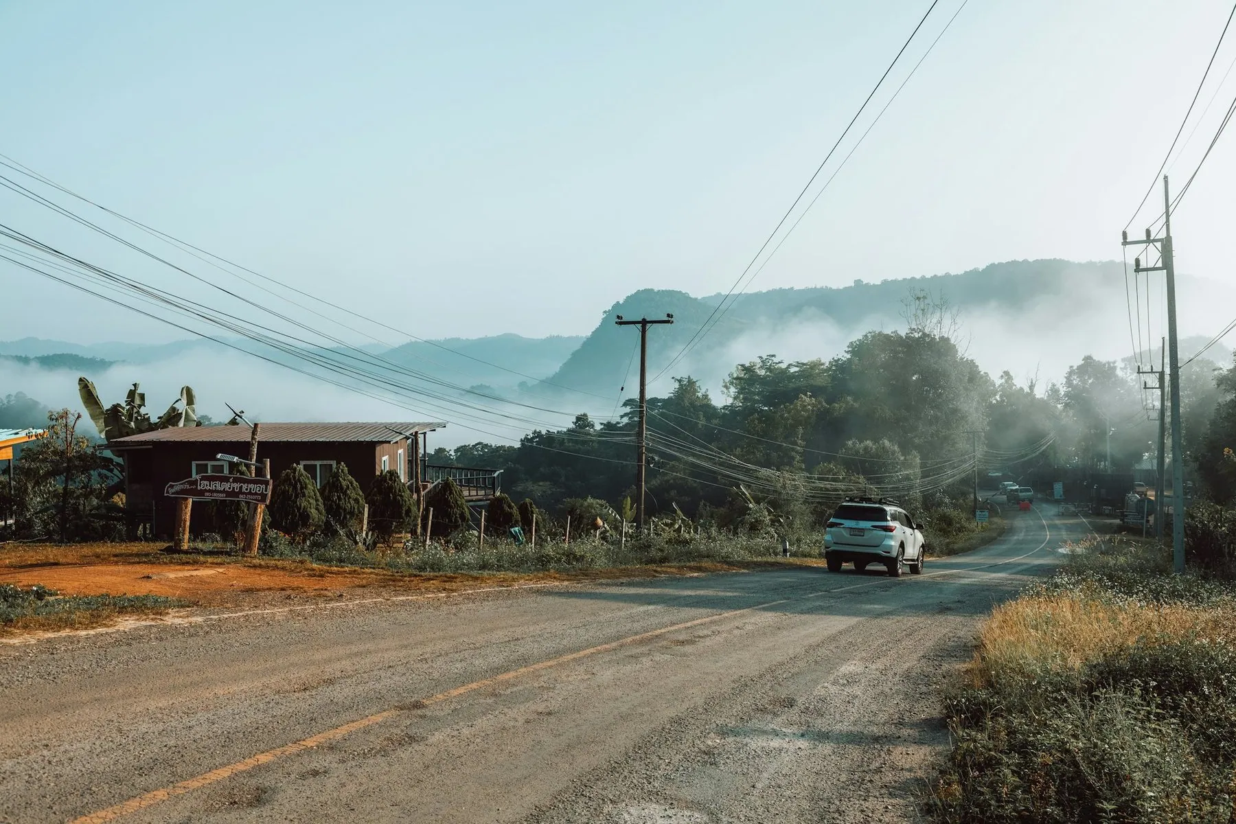 A pickup on a damp mountain road in Pang Mapha, mist hanging over the ridges ahead