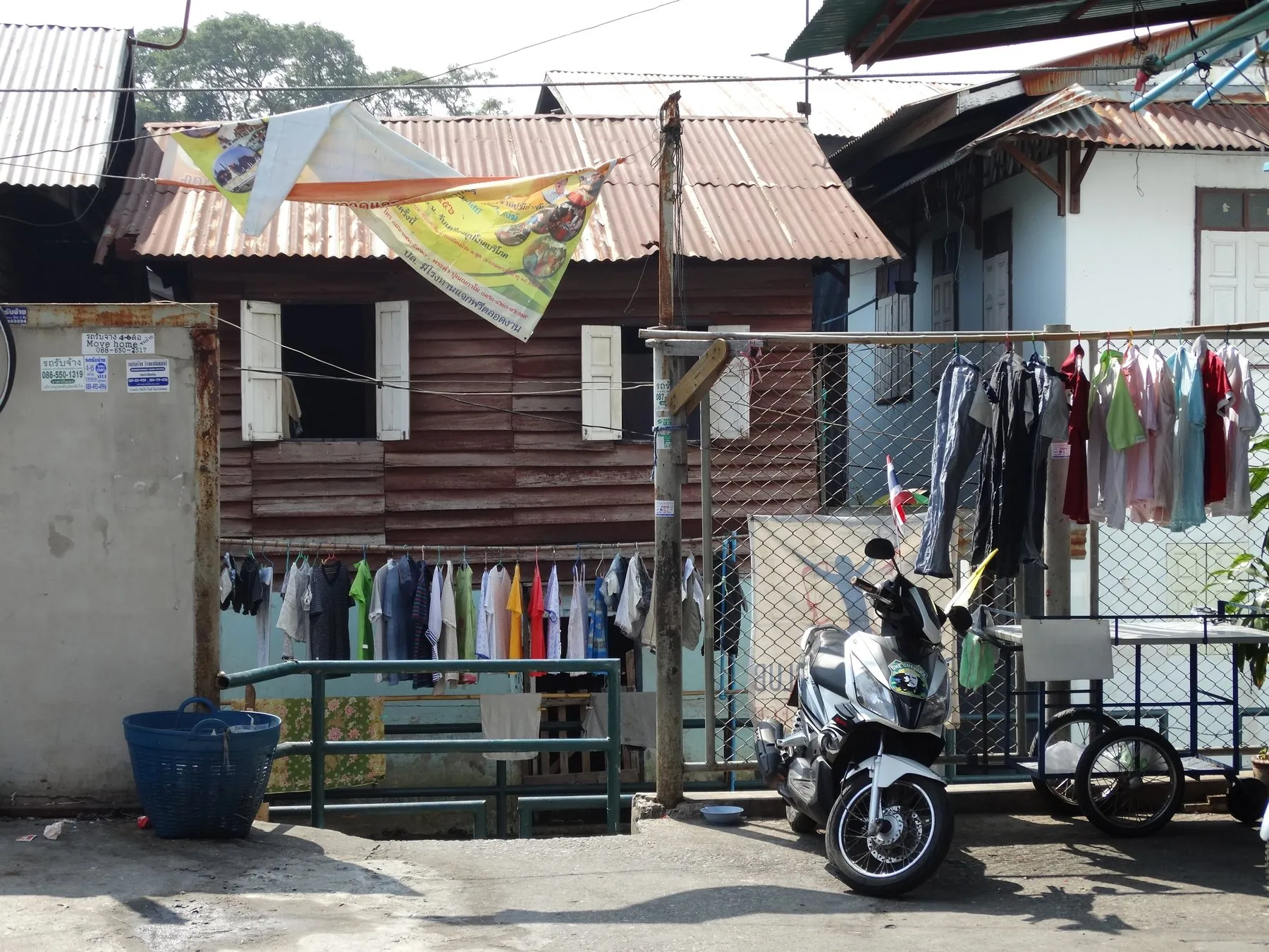 A motorbike parked outside an old wooden shophouse on a Bangkok back lane