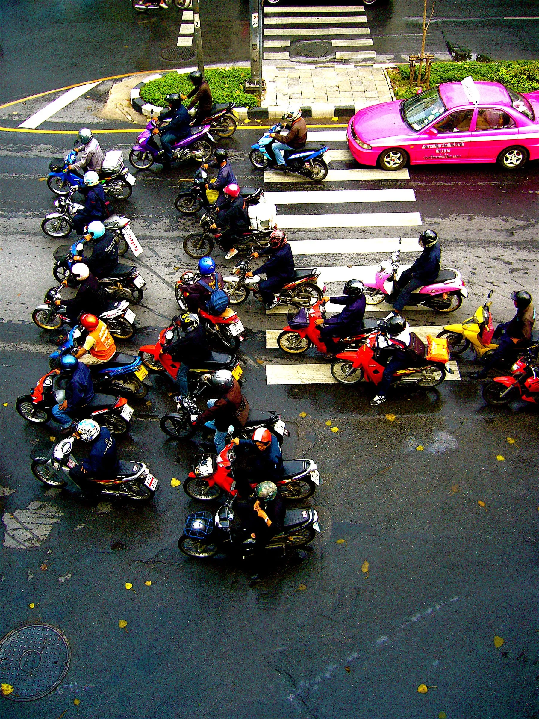 A dense block of motorbikes filling a Bangkok street between lines of stationary cars