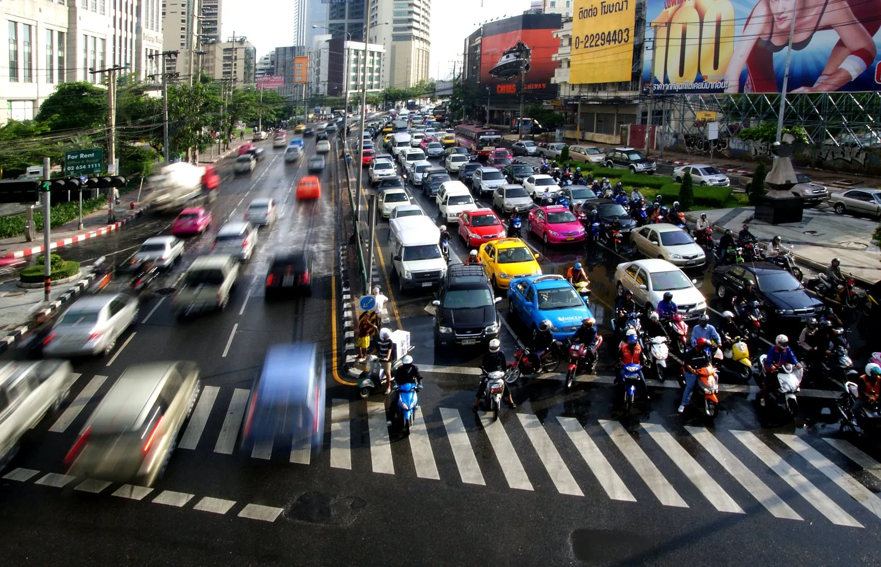 Motorbikes packed ahead of the cars at a Bangkok junction, waiting on the stop line