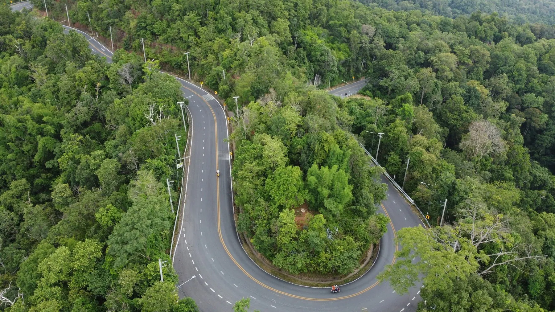 Aerial view of a road doubling back on itself in tight hairpins through dense forest on Doi Suthep above Chiang Mai