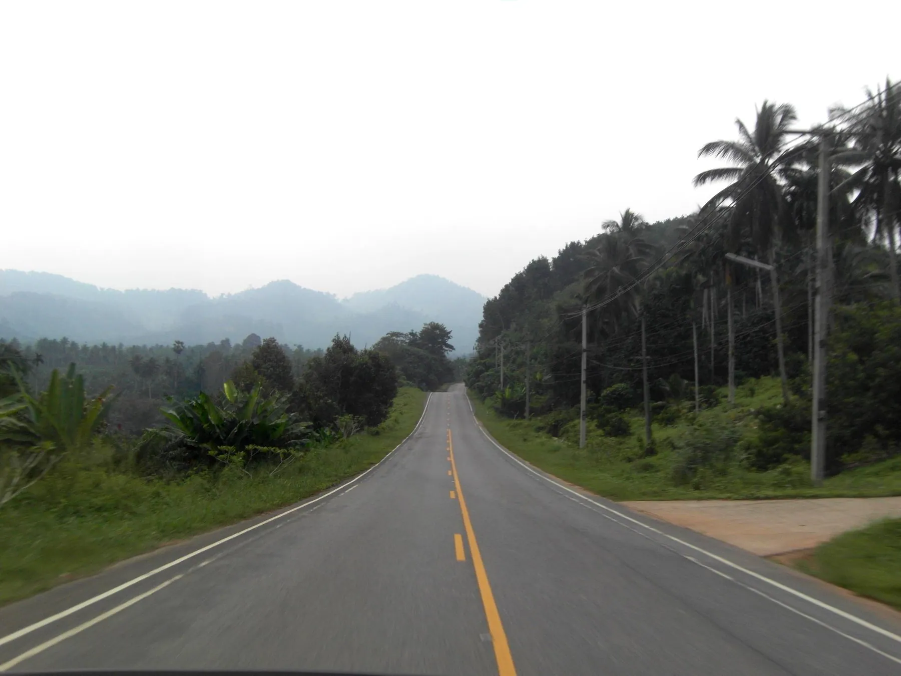 A road curving through green hills in Phato district, Chumphon province, on the Gulf coast route south