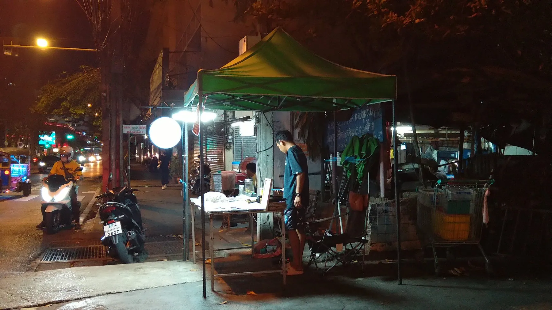 An open-fronted cannabis stall on a Bangkok pavement with jars laid out on the counter