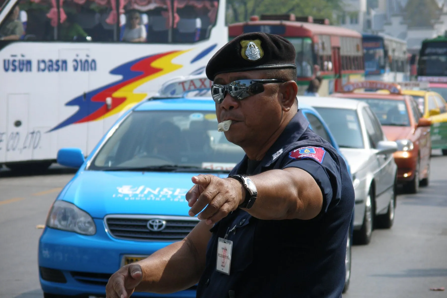 A traffic officer standing among stationary cars in central Bangkok during the evening peak