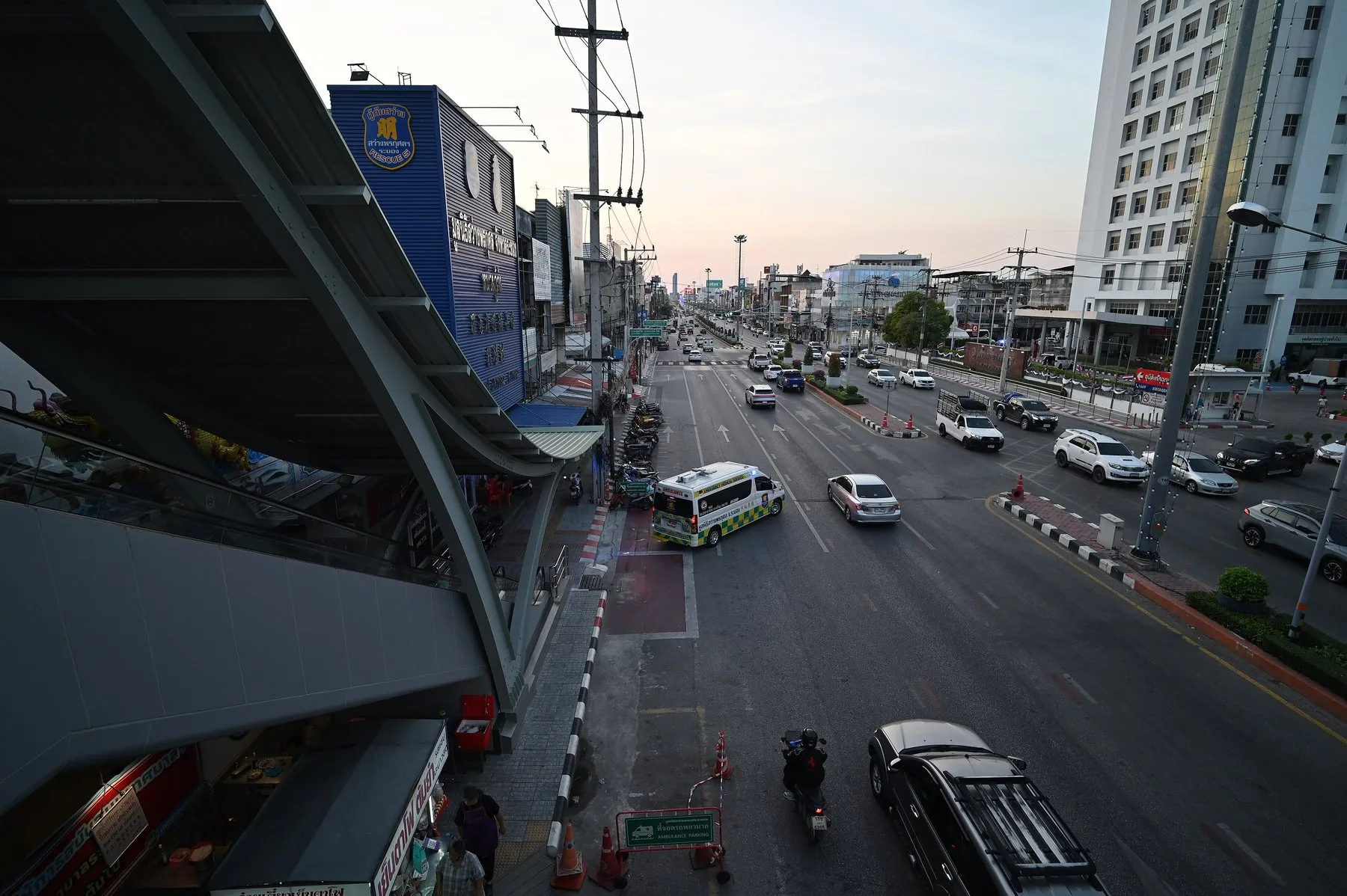 Cars, pickups and scooters sharing a busy multi-lane Thai road at dusk