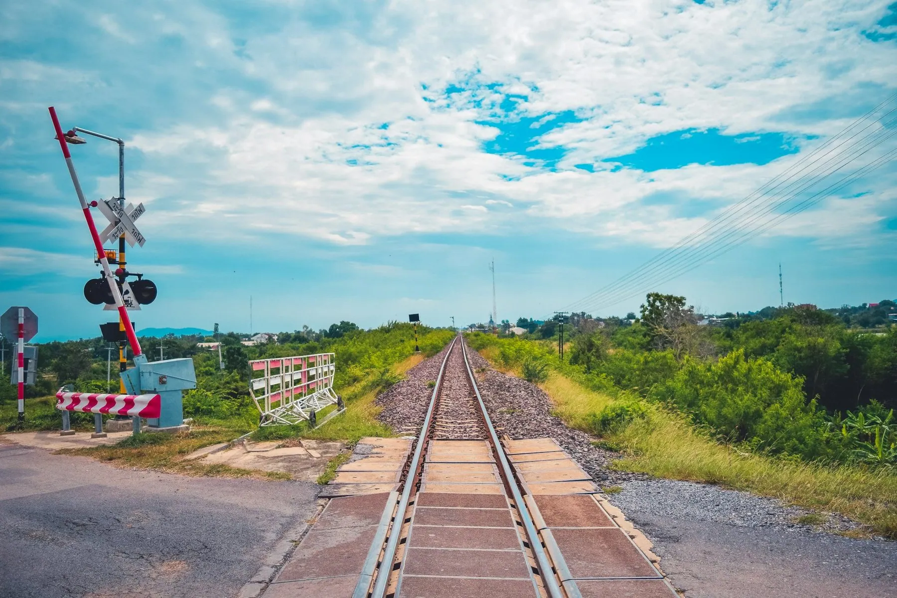 Railway track running across a road with a level-crossing signal standing beyond it