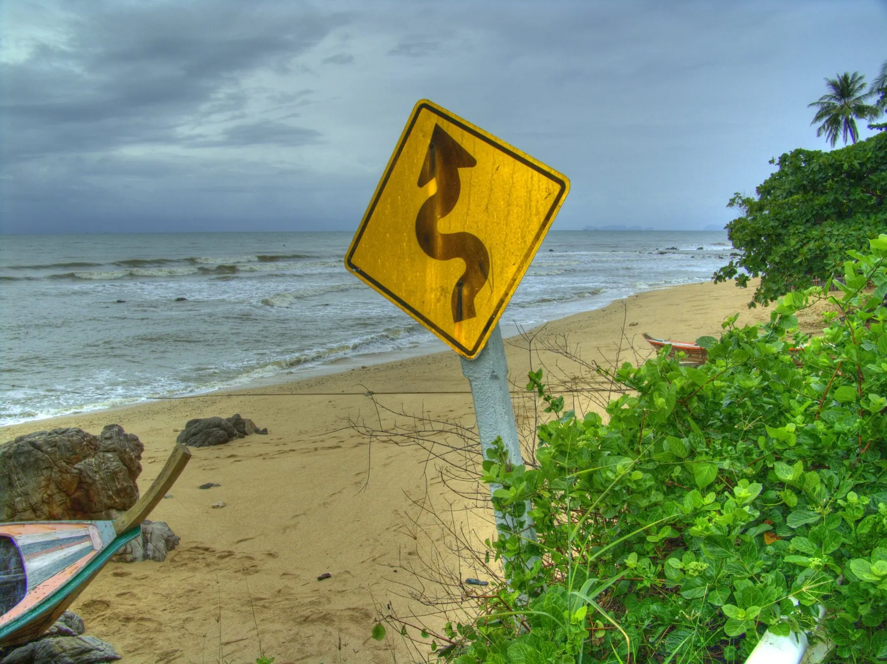 A yellow chevron warning board on a blind bend of a Thai hill road