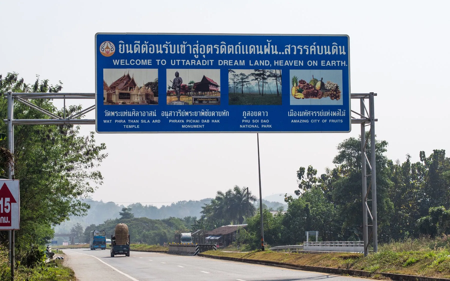 A welcome sign in Thai script arching over highway 11 at the Uttaradit provincial boundary