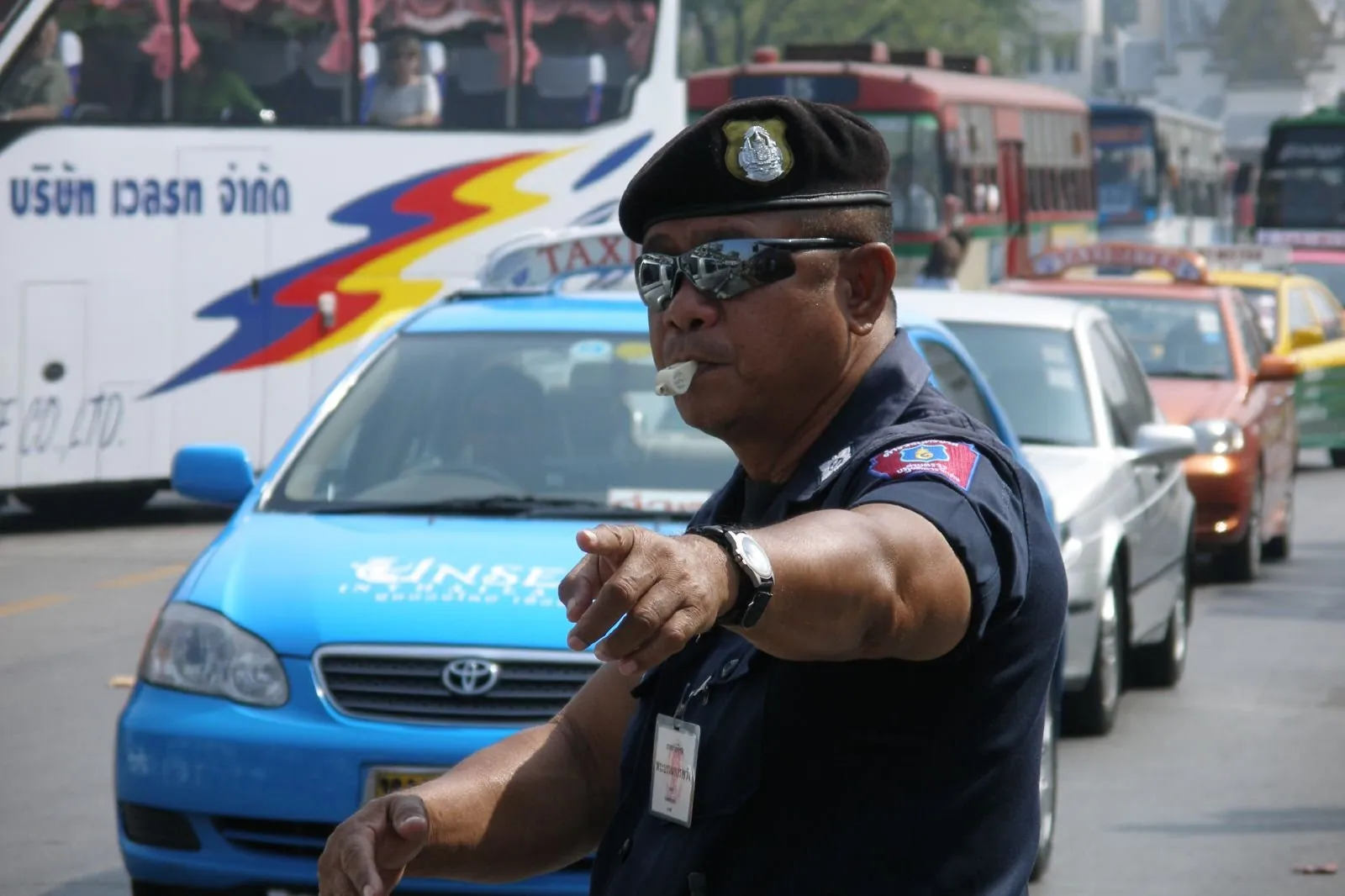 A Royal Thai Police traffic officer in brown uniform standing beside a Bangkok road