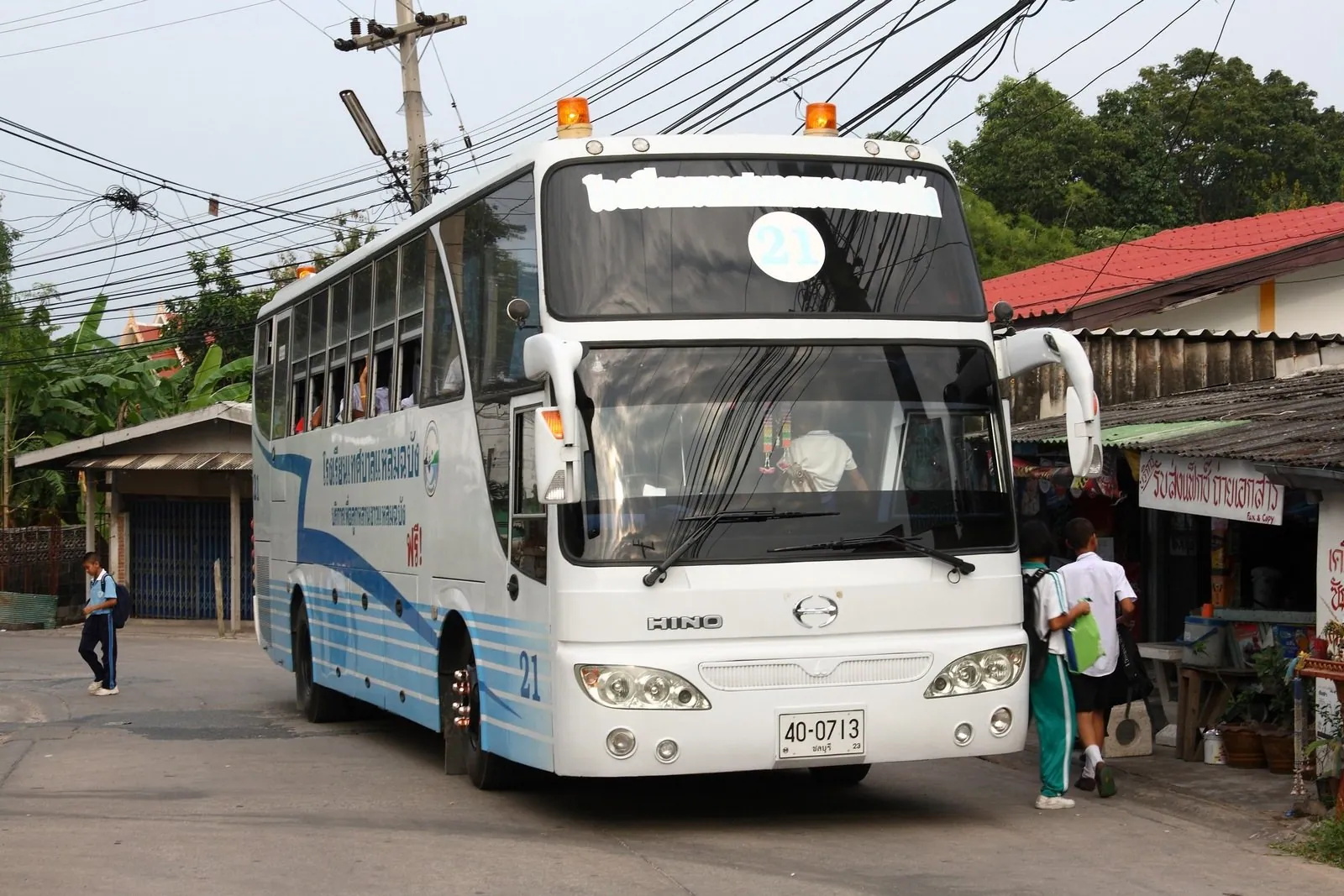 A yellow school bus lettered in Thai parked at the roadside in Laem Chabang, Chonburi