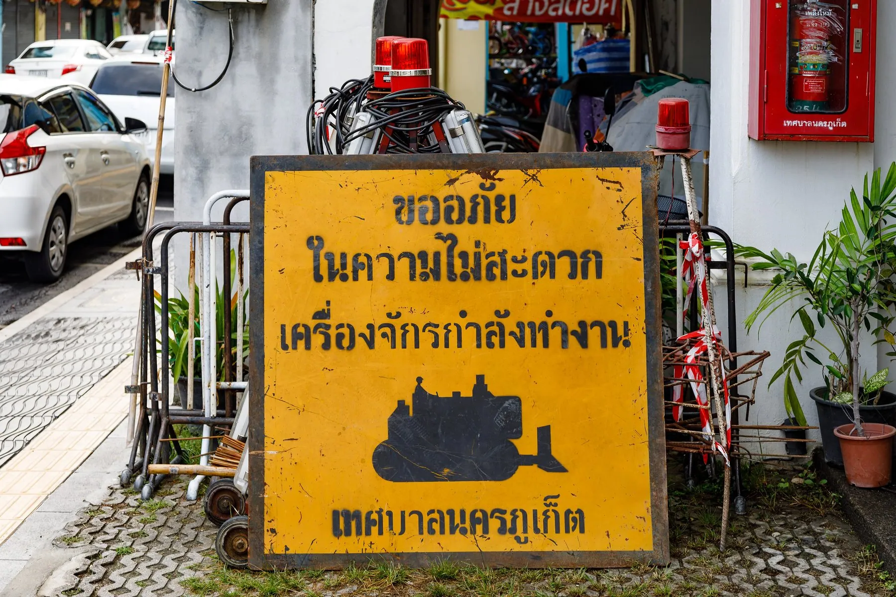 A Thai working-site sign and cones narrowing a lane in Phuket province