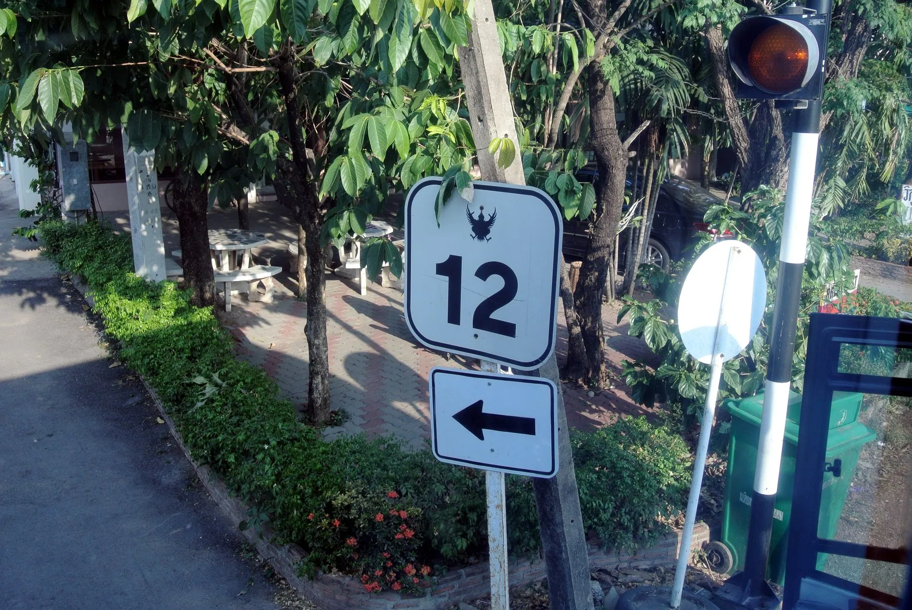 A roadside distance sign on Thailand highway 12 listing towns and kilometres in Thai and English