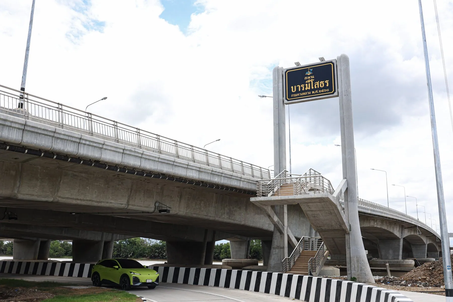 Blue Thai-script signage above the U-turn opening under the Baramee Sothon bridge