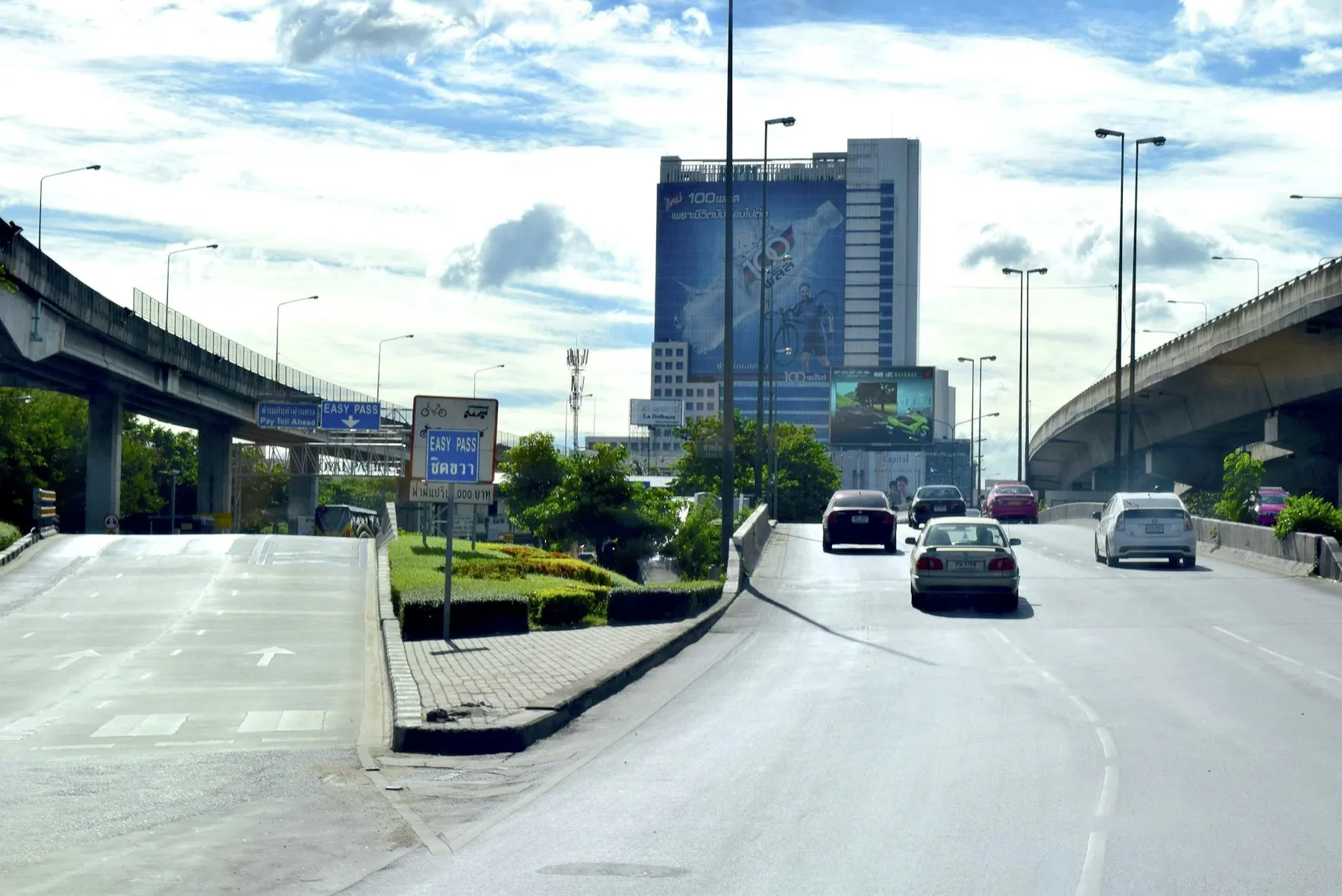 Traffic running under and over a stack of elevated expressway ramps in Bangkok on a bright day