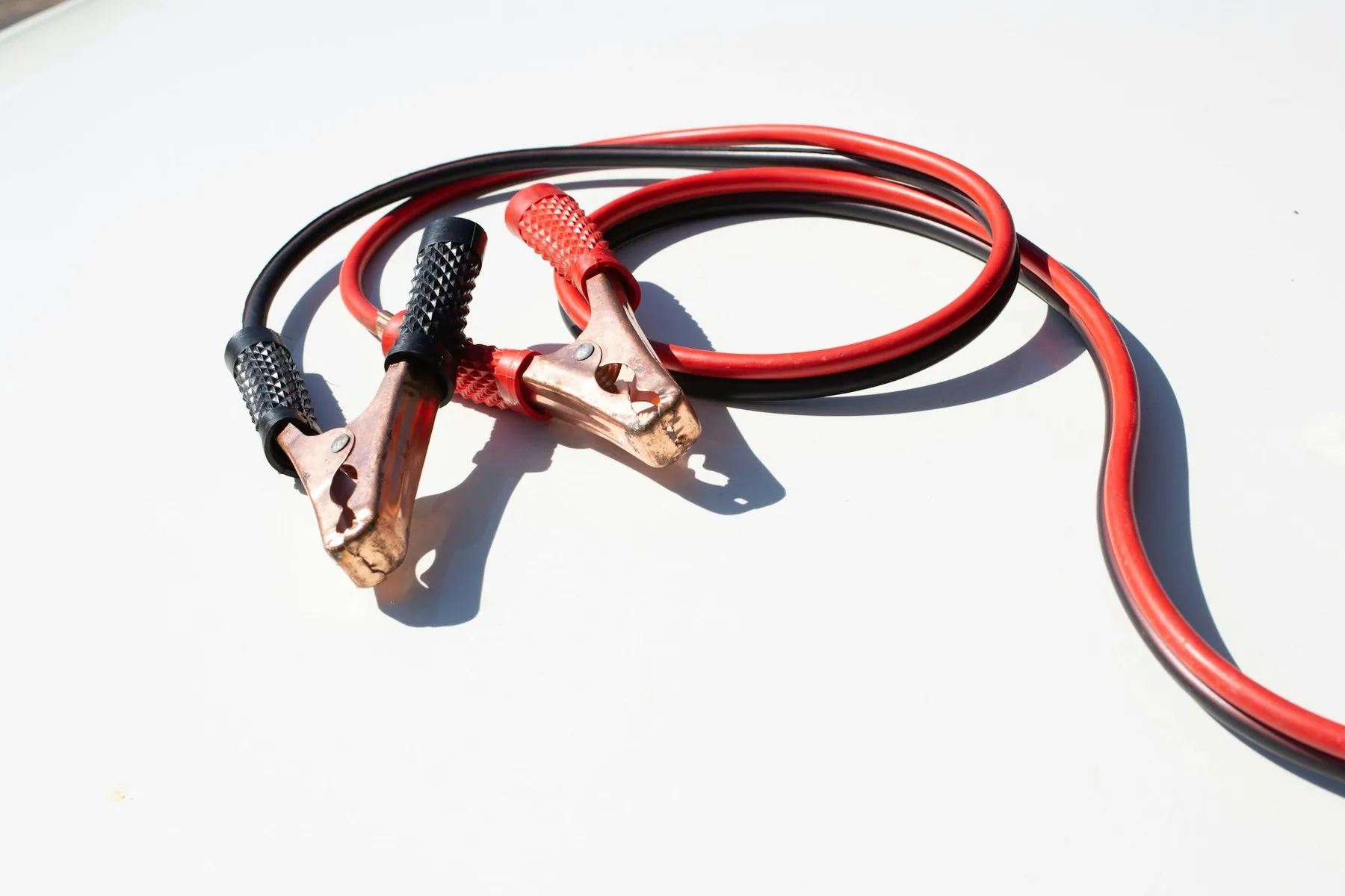 A coiled pair of red and black jump leads with copper crocodile clips