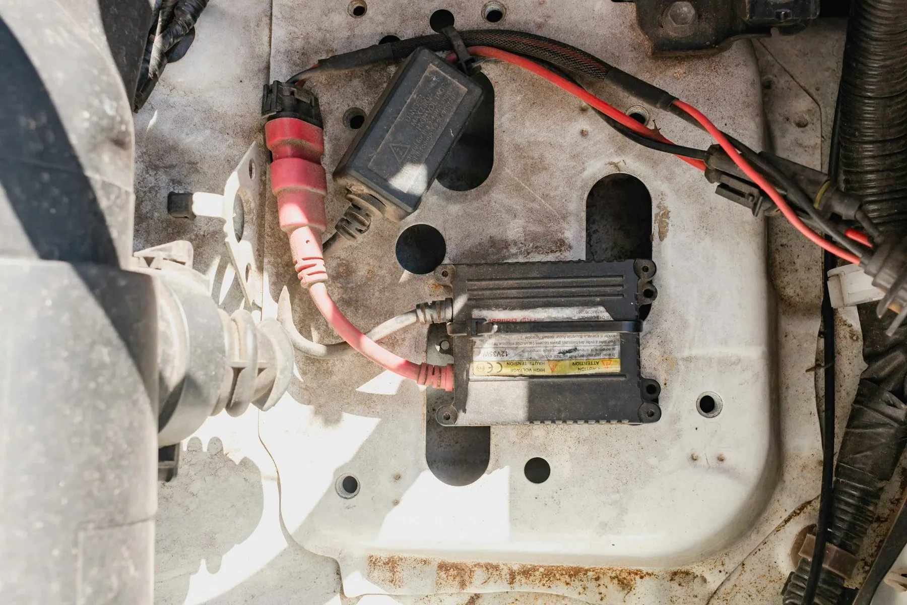 A car battery in its tray with red and black jump-lead clamps bitten onto the terminals