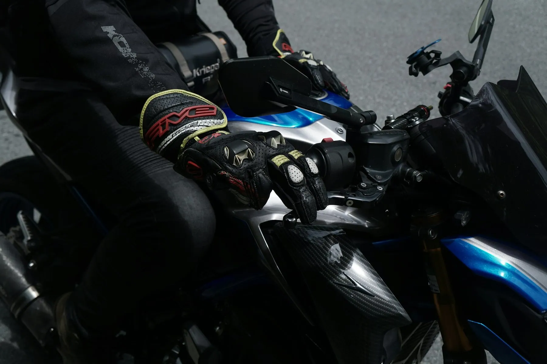 A rider's gloved hands resting on the grips and controls of a motorbike
