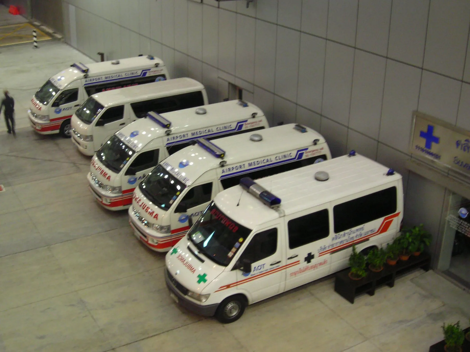 A row of white airport medical clinic ambulances parked nose-in at Suvarnabhumi Airport