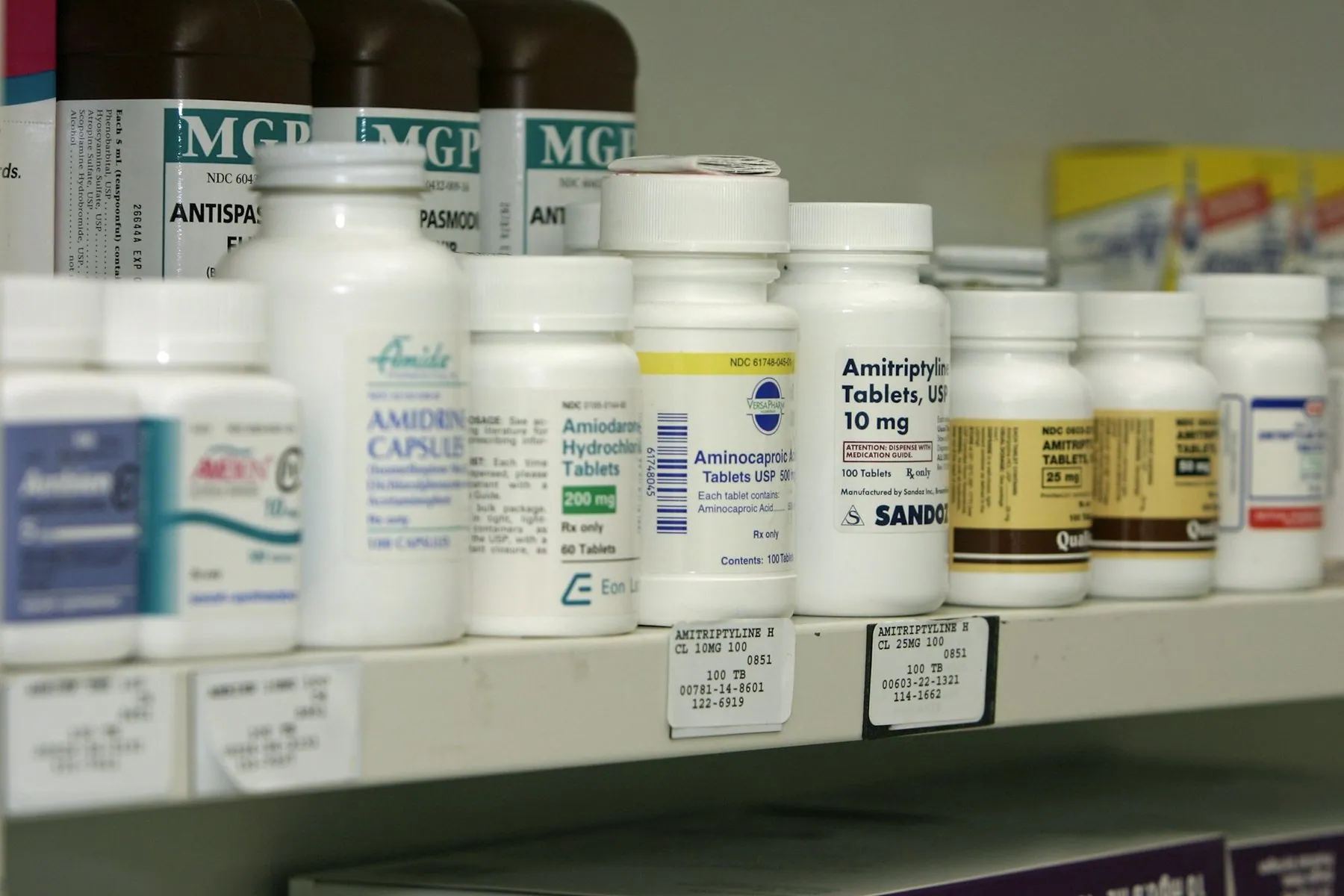 A pharmacy shelf lined with white and amber medicine bottles behind the counter