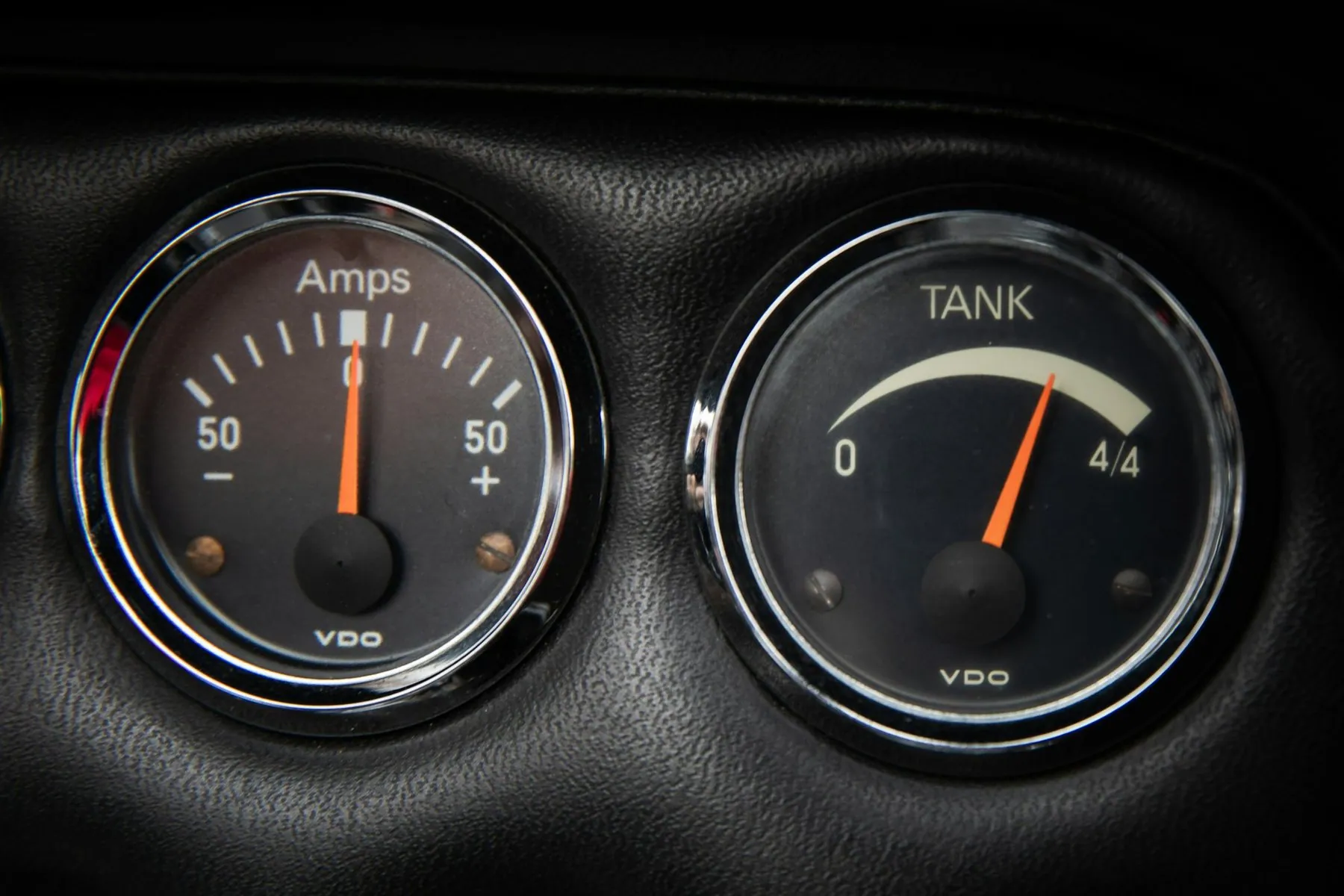 Two round dashboard dials, the right one marked TANK with the needle close to empty
